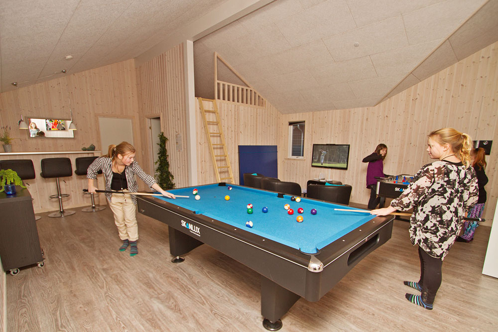 Sportliche Gäste treten im Aktivitätenraum gegeneinander in Billard/ Tischtennis, Kicker und Dart an
