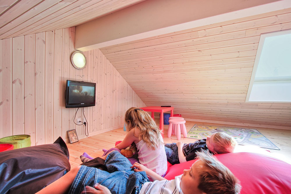 Ein Dachgiebel ist als Kinderecke mit Kindermöbeln, Autoteppich und Flachbildfernseher mit DVD-Spieler eingerichtet